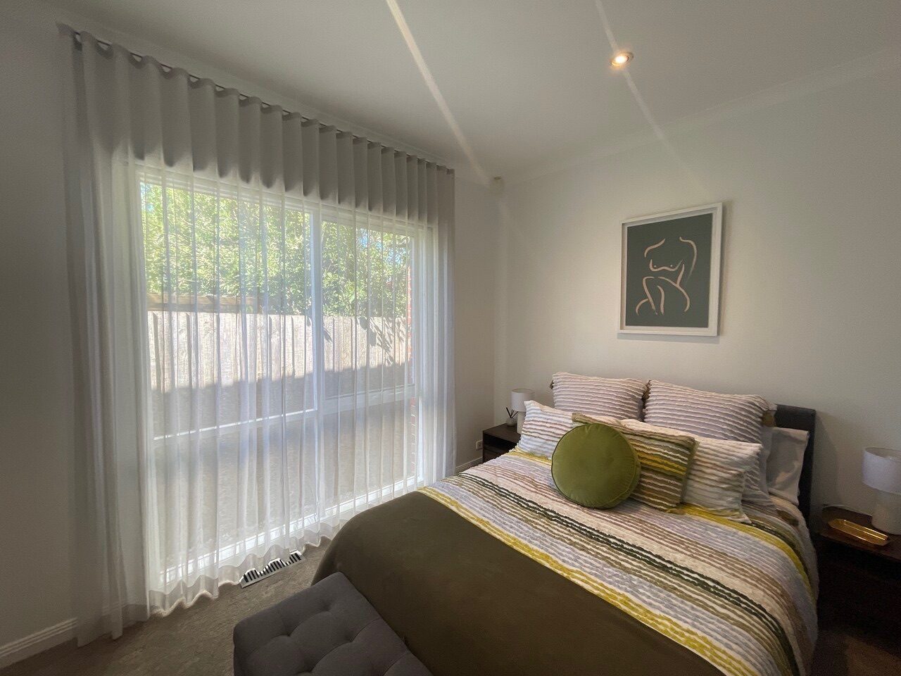 Blockout roller blinds and sheer curtains fitted in a main bedroom — Melbourne house