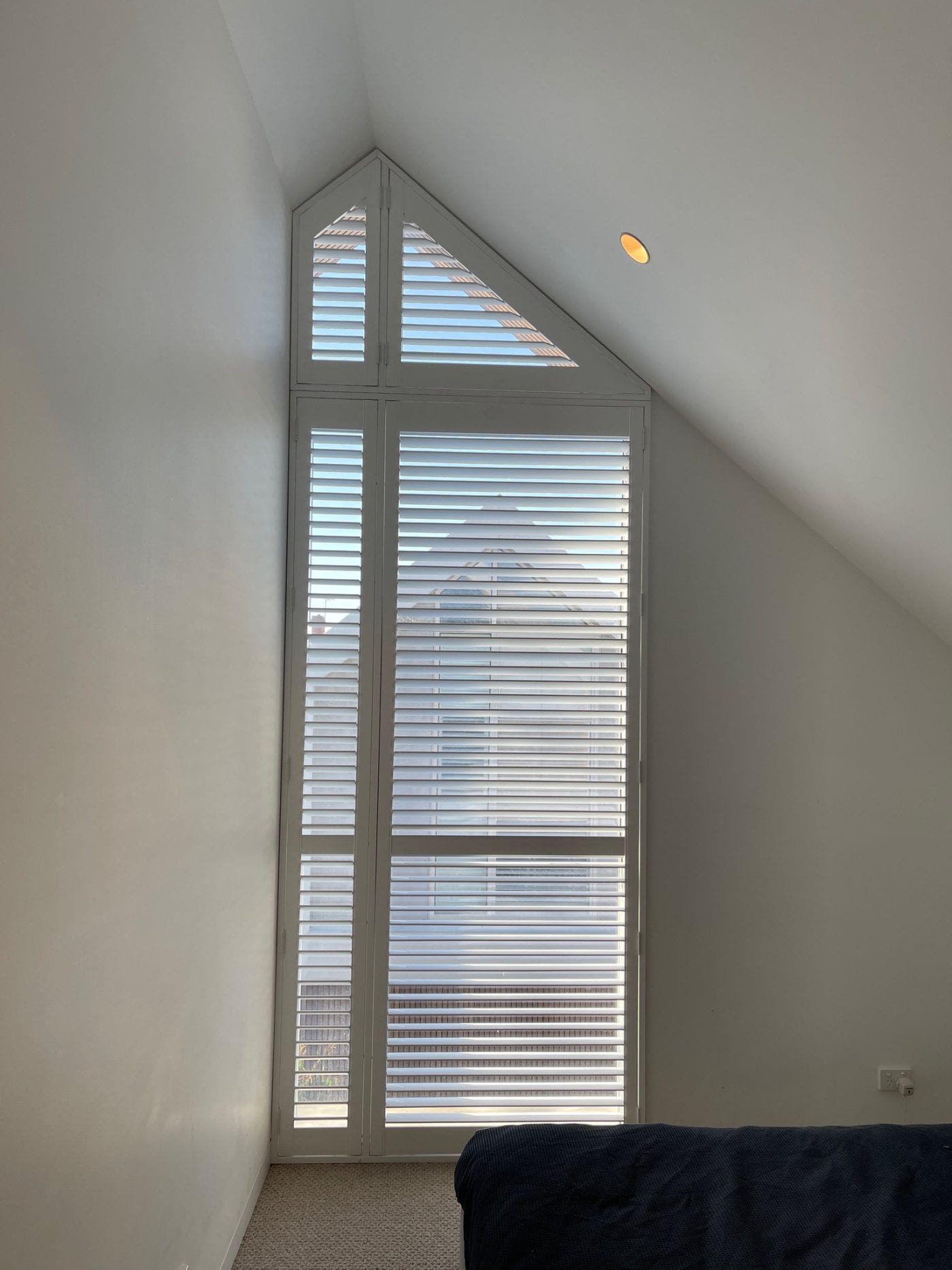 Plantation shutters on corner windows in a Melbourne master bedroom