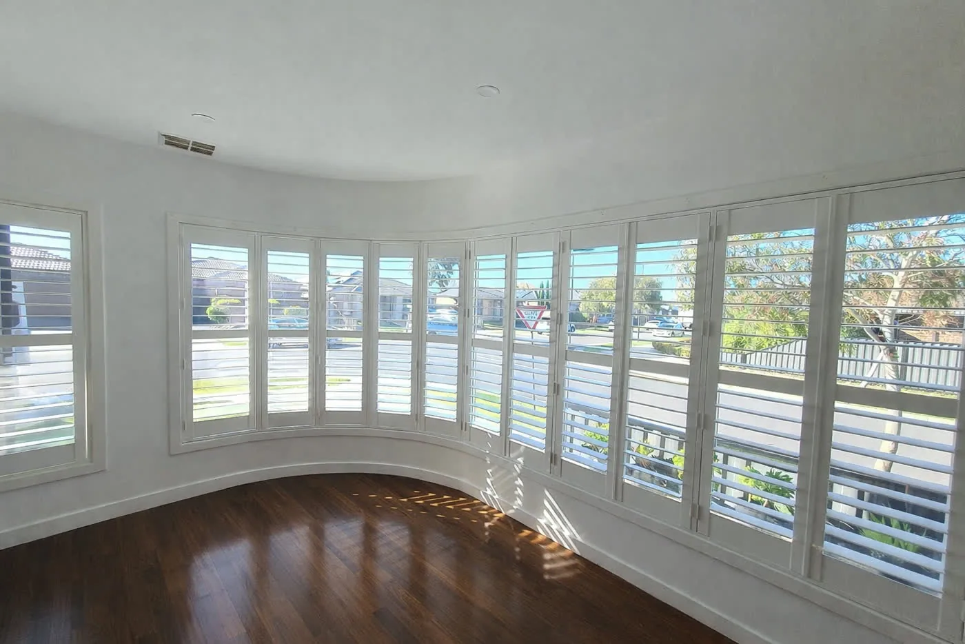 Plantation shutters fitted to a curved bay-style window in a Melbourne home — We Inspire Blinds