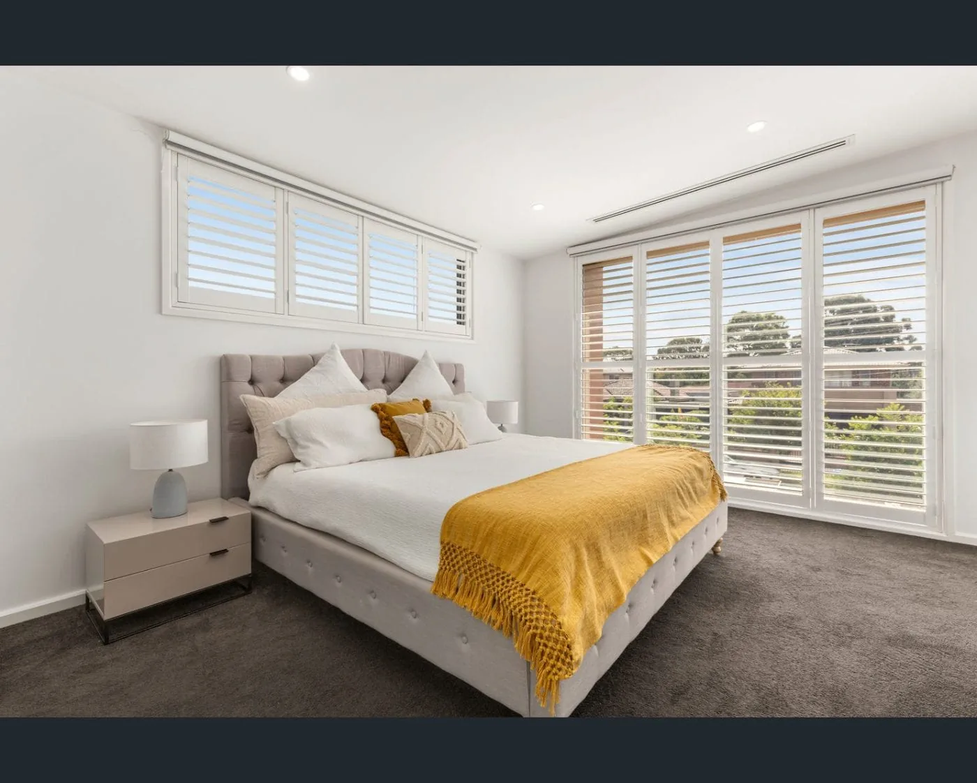 Plantation shutters with layered roller blinds in bedroom Melbourne